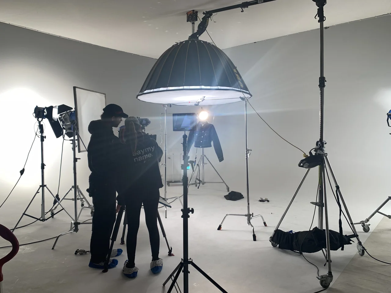 Professional photo studio with camera team, large ring light softbox and model during a shoot