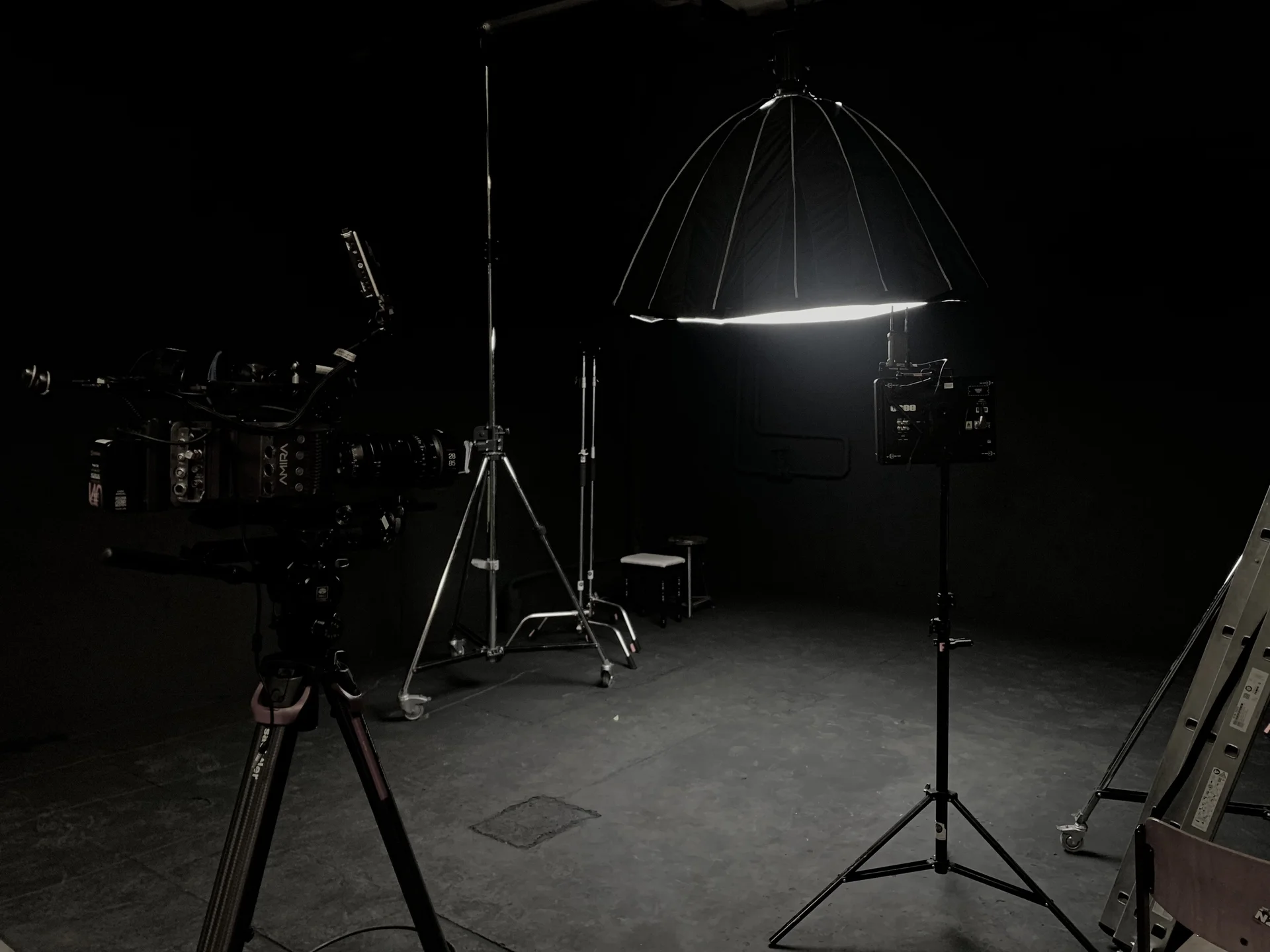 Schwarzer Raum. Professionelles Fotostudio-Setup mit Kamera, Scheinwerfern und Softbox-Beleuchtung auf dunklem Hintergrund.